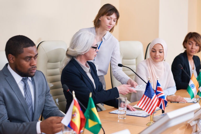 Young secretary giving documents to one of intercultural delegates